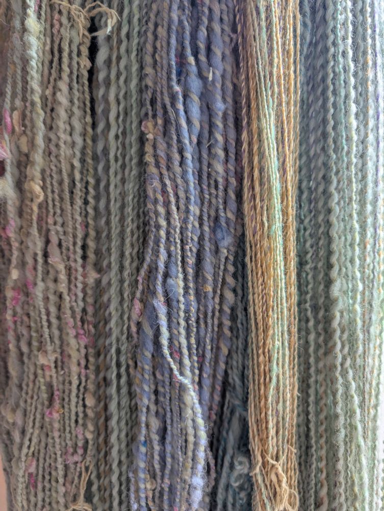 Close up of many strands of hand spun yarn in pastel colors 