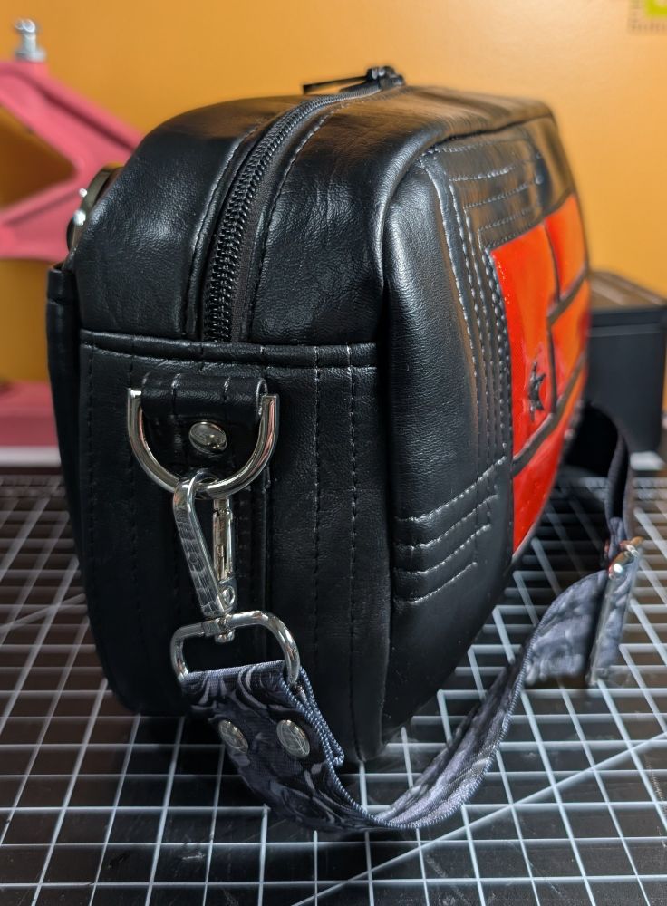 View of side gusset of a black faux leather bag 