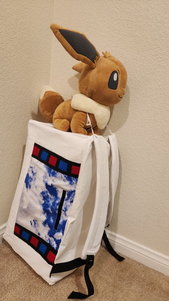 large eevee plush atop a boxy white backpack