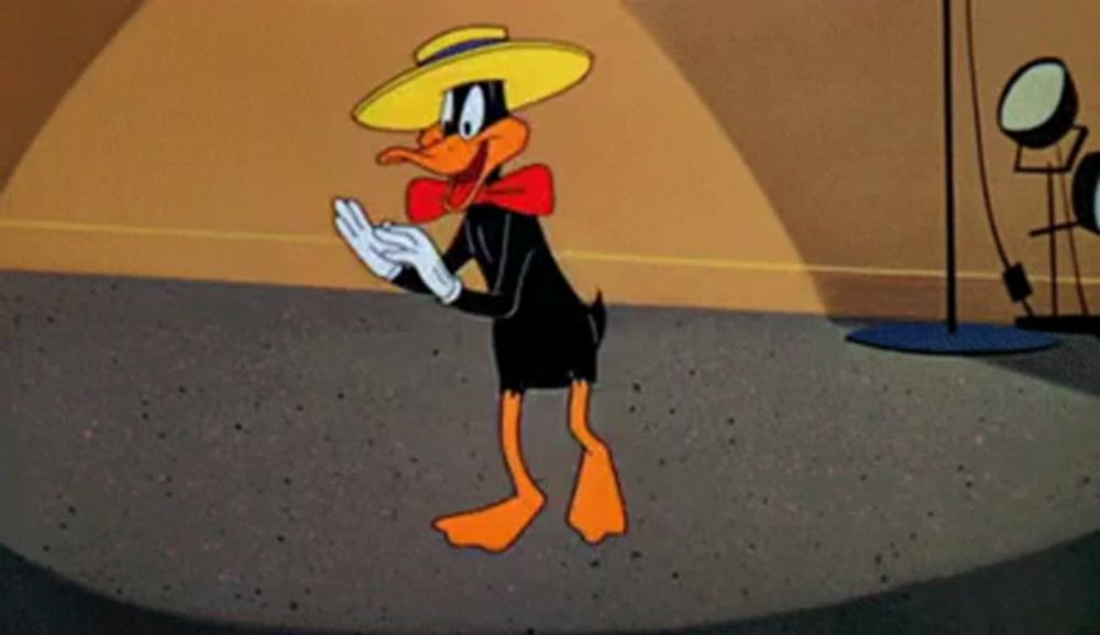 a cartoon duck wearing a hat and bow tie is clapping