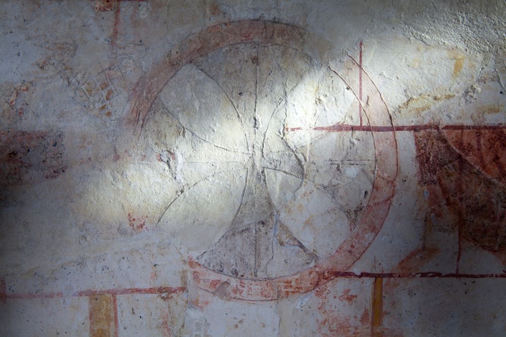 C12th Maltese consecration cross illuminated by a shaft of light that shows it is deeply incised into the plaster of the wall, red and yellow paint remnants remain. Image (c) Andy Marshall