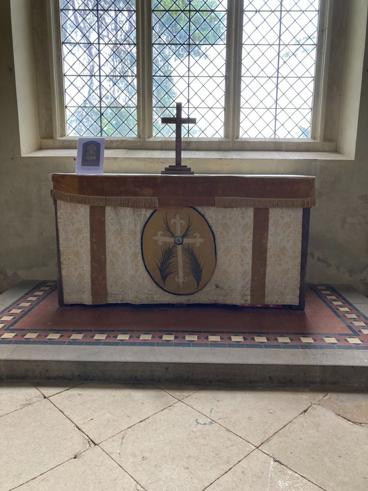 The altar frontal in place on the altar after successful restoration. The colours of the fabric are gold, cream and yellow and the central motif is a cross with two palm leaves.
