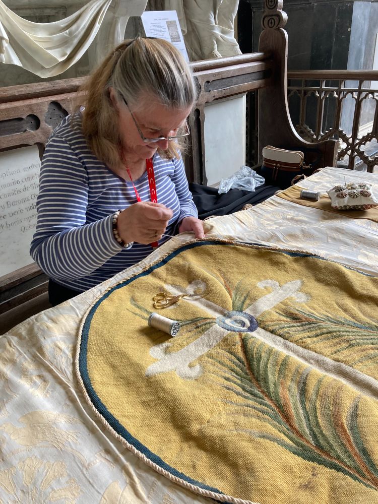 Close up of Wendy, sitting over the altar frontal sewing the cord back into place.