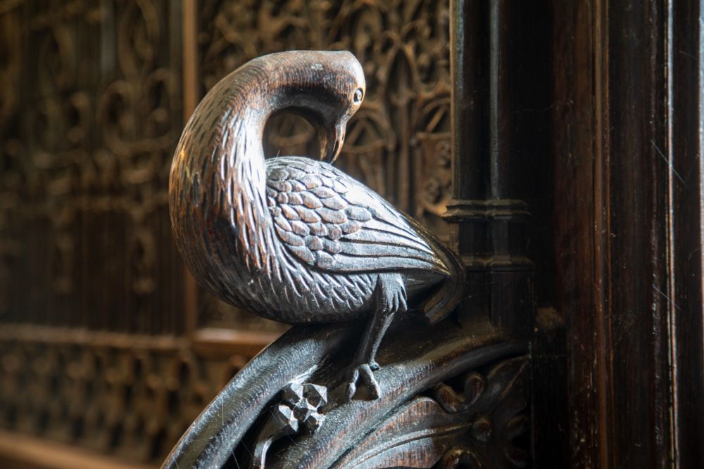 A beautiful carved wooden bird, bending it's neck back to preen it's feathers at St. Wilfrid's, Brougham (c) Andy Marshall