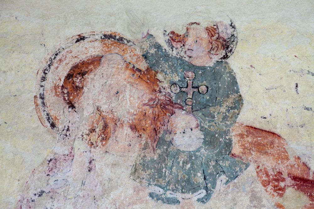 Wallpainting detail of St. Christopher carrying Baby Jesus on his shoulder. St. Christopher and the Christ Child both have flaming red hair and St. Christopher has a red beard. The Christ Child wears a green robe and blesses St. Christopher with his right hand, holding an orb in his left. (c) Andy Marshall