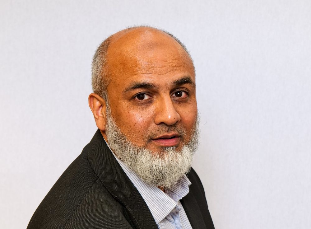 Portrait of Inayat in front of a grey background