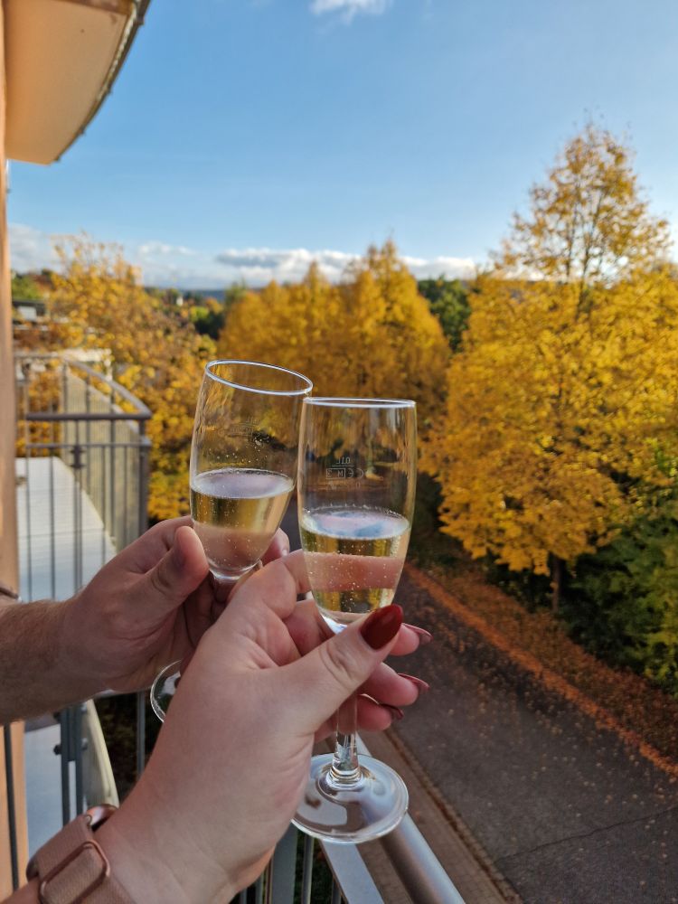 foto von zwei sektgläsern auf einem hotelbalkon. im Hintergrund herbts 