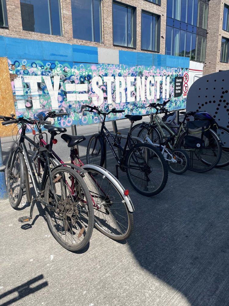 3 bike stands. Bike bunker in the background. 6 bikes locked to the stands.