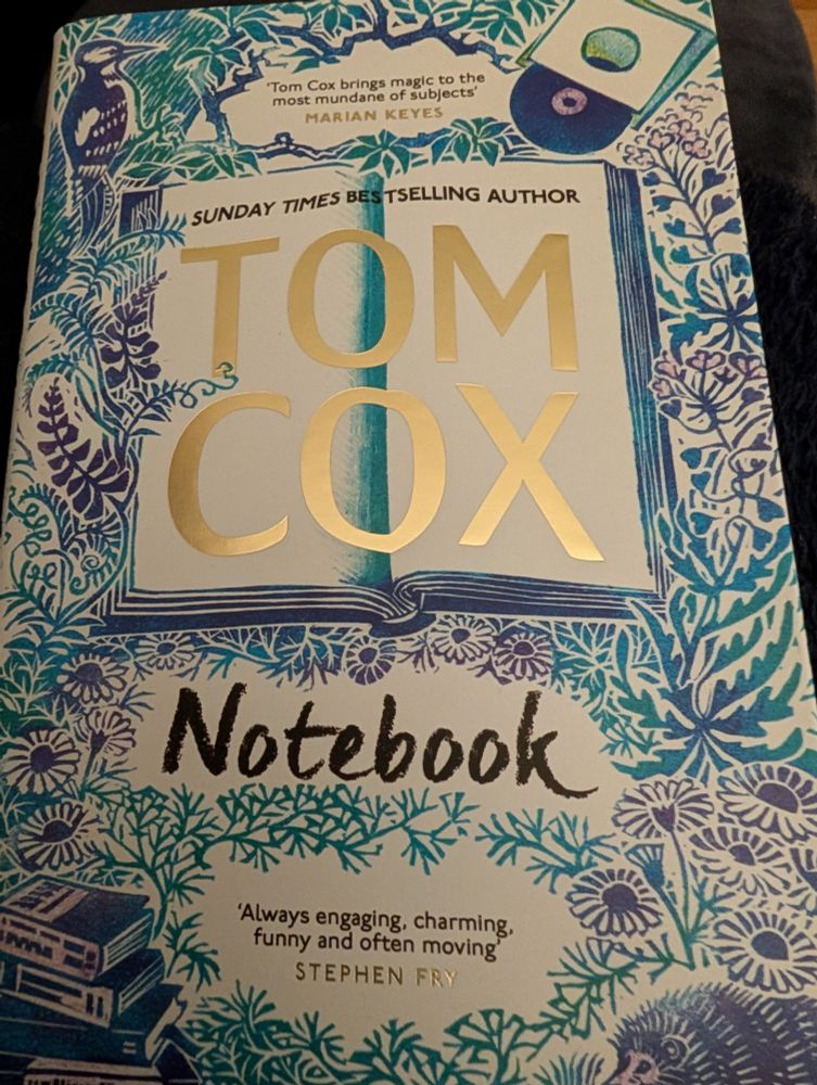 Cover of The Notebook by Tom Cox. Also features a woodpecker, some vinyl records, a pile of paperbacks and a hedgehog in the bottom right hand corner. 