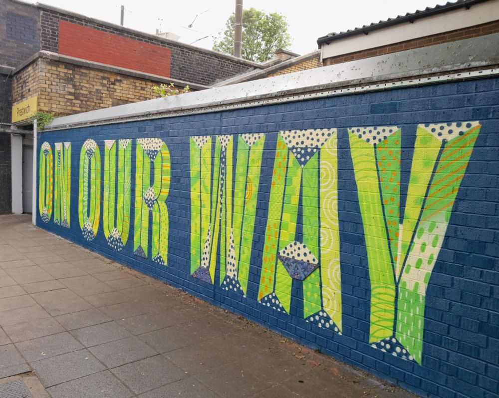 A colourful street art mural saying On Our Way. Its on a wall next to Prestwich metrolink statiin, Manchester