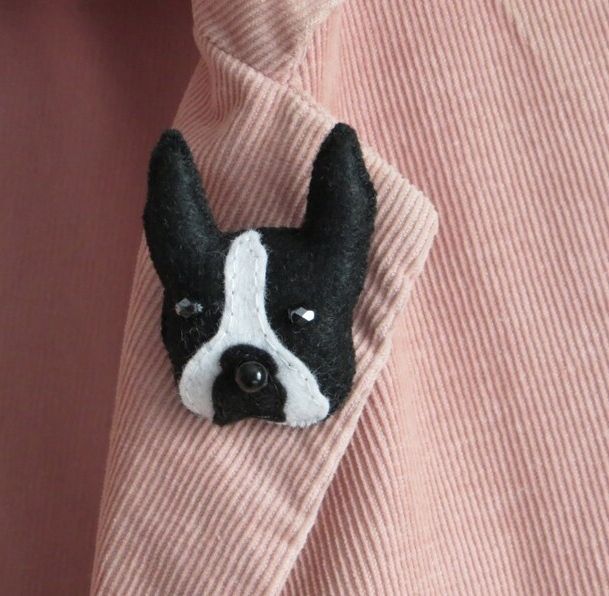 A handmade felt boston terrier dog head brooch pin by misheleneous attached to a pink corduroy jacket lapel