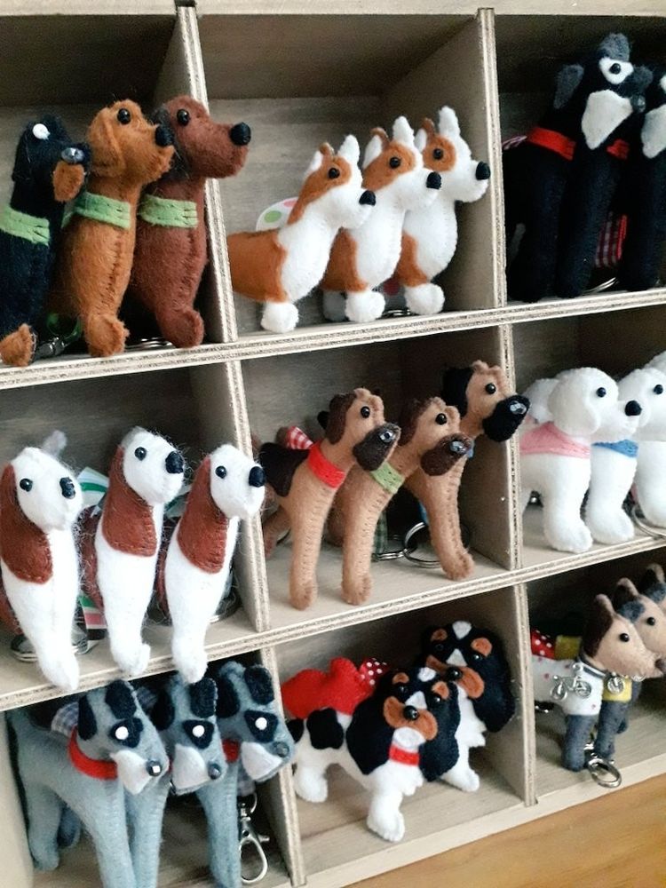 A small wooden shelving unit filled with lots of handmade felt kennel club dog breed keyrings by misheleneous