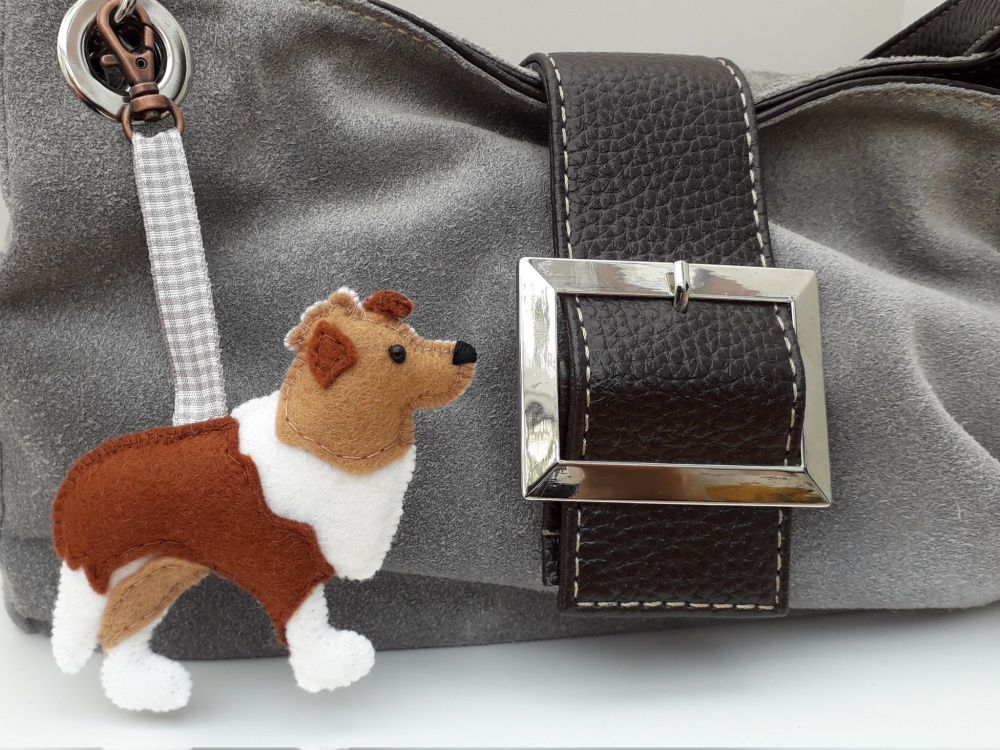 A handmade felt Rough Collie dog charm by misheleneous. Attached to a grey suede handbag