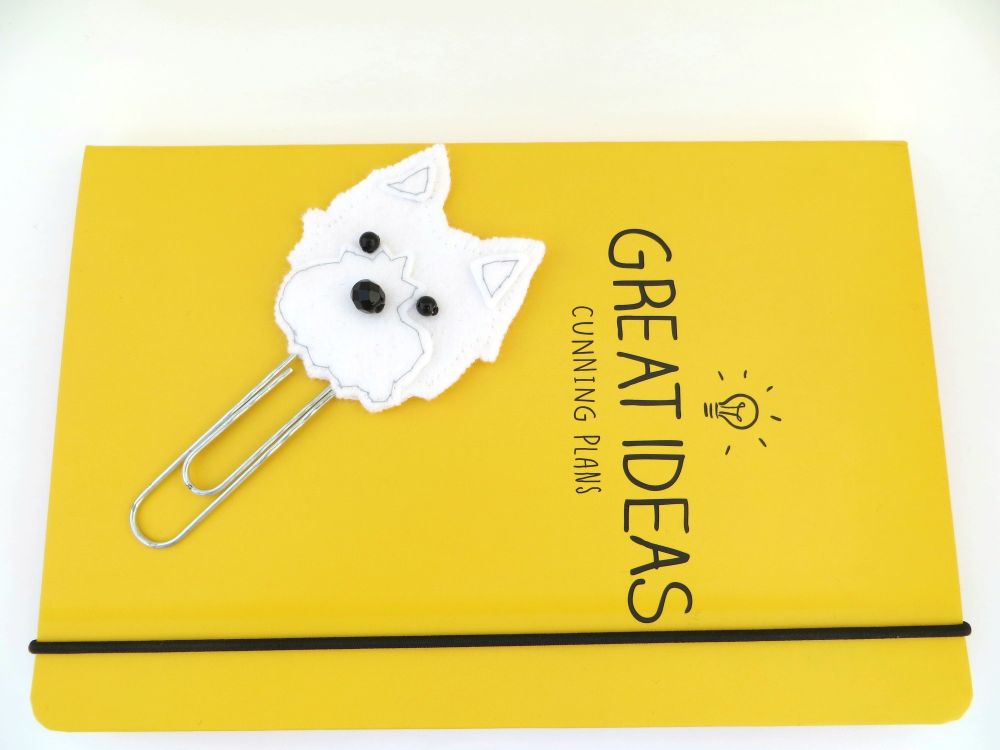 A handmade felt westie dog planner clip or book mark by misheleneous. Picured on a yellow journal
