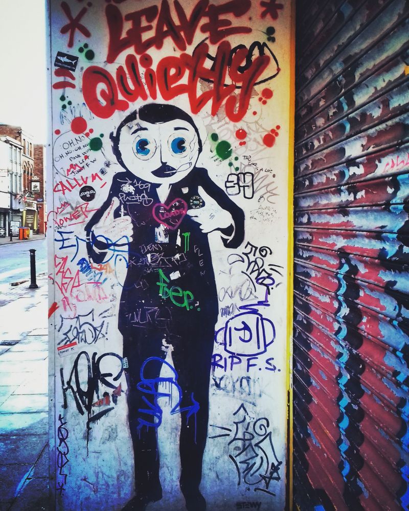 Frank Sidebottom stencil surrounded by graffiti on Oldham Street, Manchester