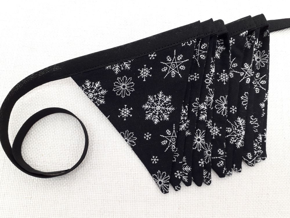 A concertinaed length of black and silver snowflake print fabric bunting by misheleneous displayed flatlay