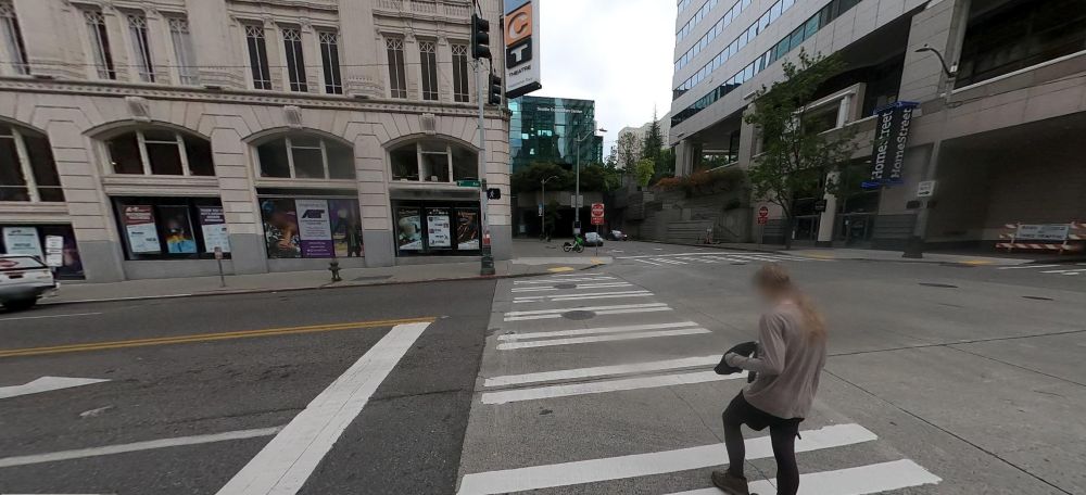 image 3/7 next to flower pot that is out of frame. Looking forward is stone building with parking garage on the right across street