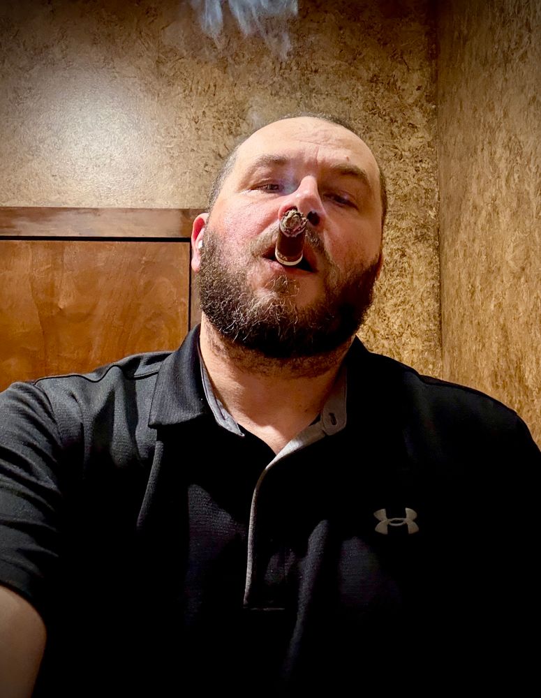 Bearded cigarman enjoying a cigar and a piss