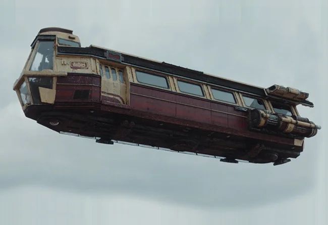Passenger flying transport from S1 of Star Wars: Andor. It is burgundy with beige accents and looks like a tram car that could fall to bits at any minute. 