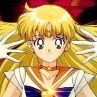 Sailor Venus. a young woman with long blonde hair wearing a sailor uniform with orange accents a star choker and an orange jewel head band and blue bow tie.
