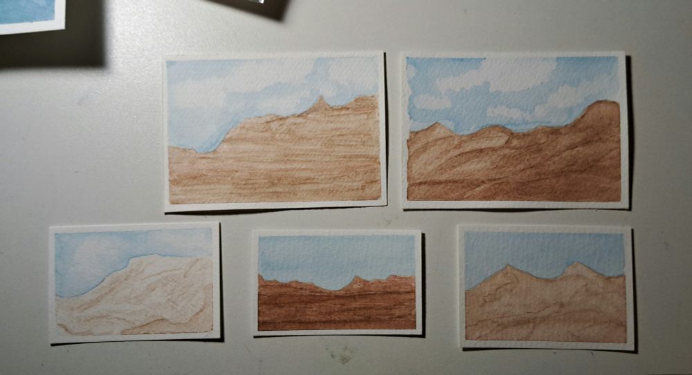 A photograph of five small watercolor paintings depicting desertscape / Grand Canyon inspired landscapes. The two on the top are bigger than the three miniatures on the second row