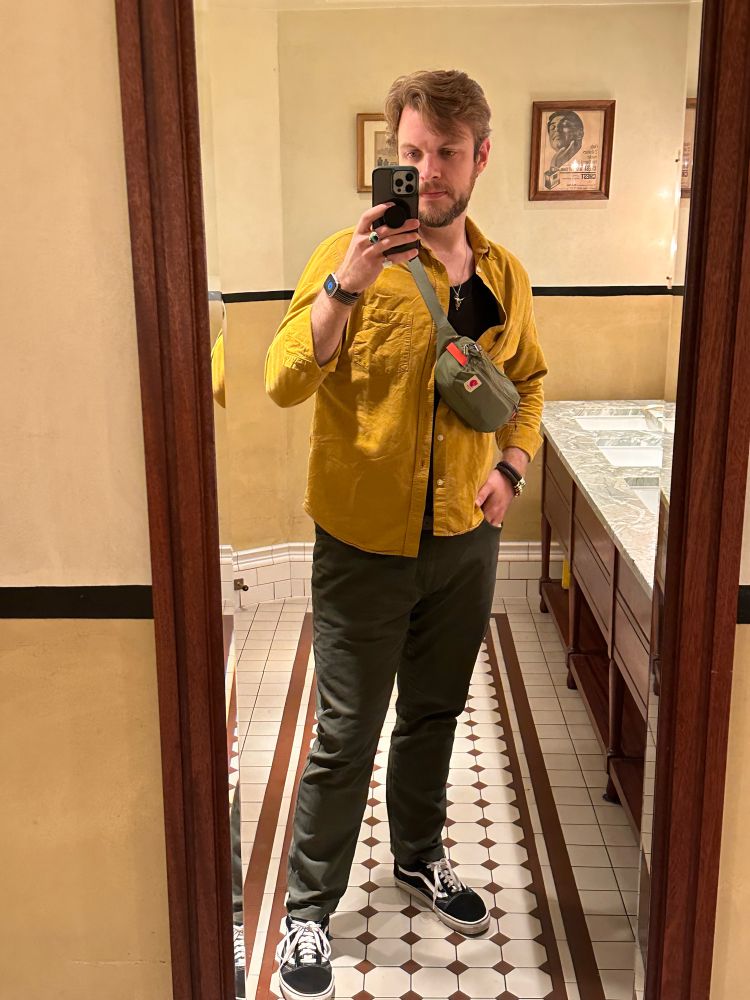 Restaurant bathroom full-length mirror selfie. Wearing a yellow shirt and green pants with vans. A green Fjallraven bag slung over my chest