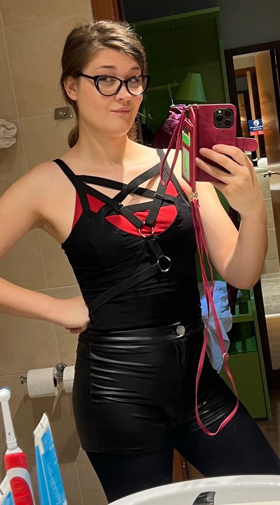 Casual fit Marii hotel mirror selfie, in a black strappy sleeveless top, red Bradley, shiny black shorts nand tights