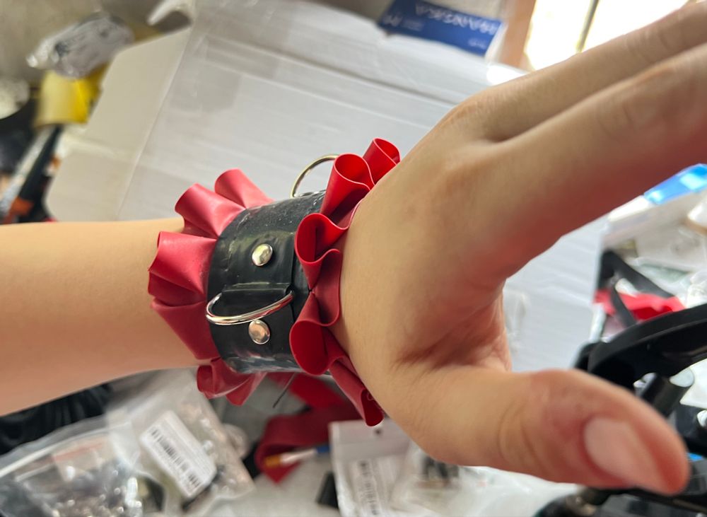 Hand wearing a red n black frilly maid cuff
