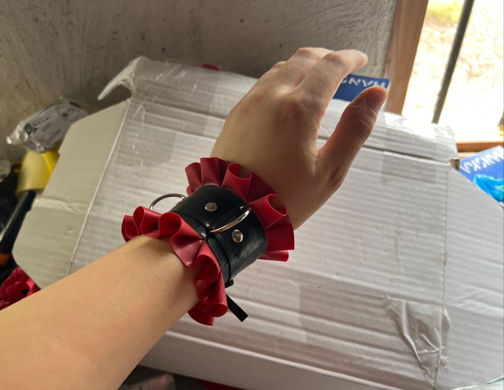 Hand wearing a red n black frilly maid cuff
