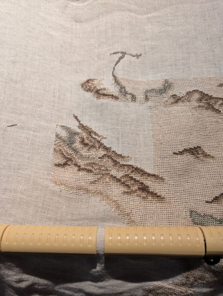 A photo of my outgoing progress with my Skyrim cross stitch map project. This section is the easternmost edge of the Reach near Karthwasten. The mountains to the southwest are mostly fleshed out and the ones along the northern border are taking shape. The meandering Karth river is also beginning to be visible in the lower half of the piece. 
