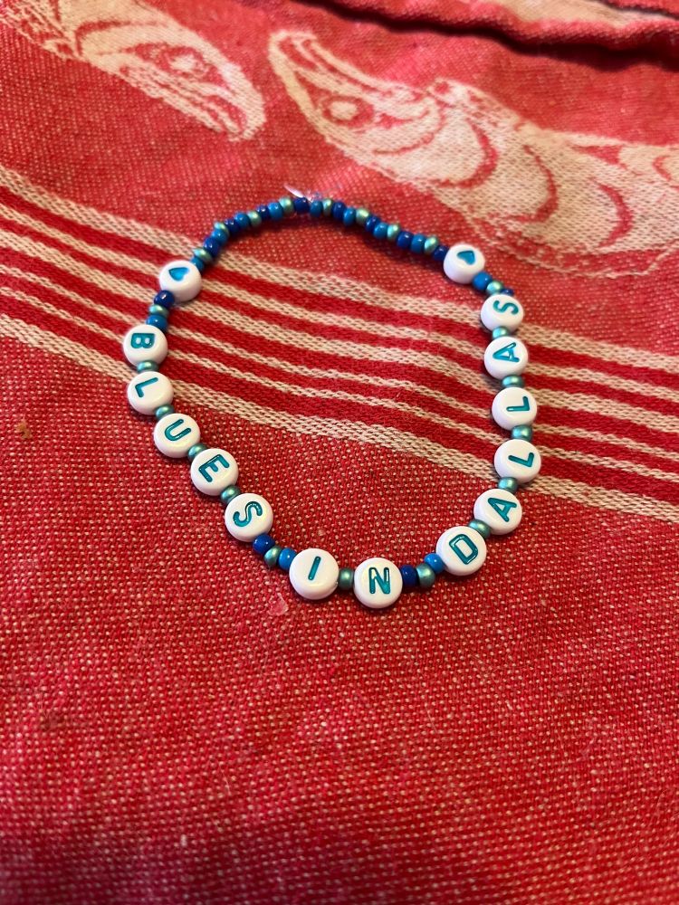blue beaded bracelet with “blues in dallas” in blue letters