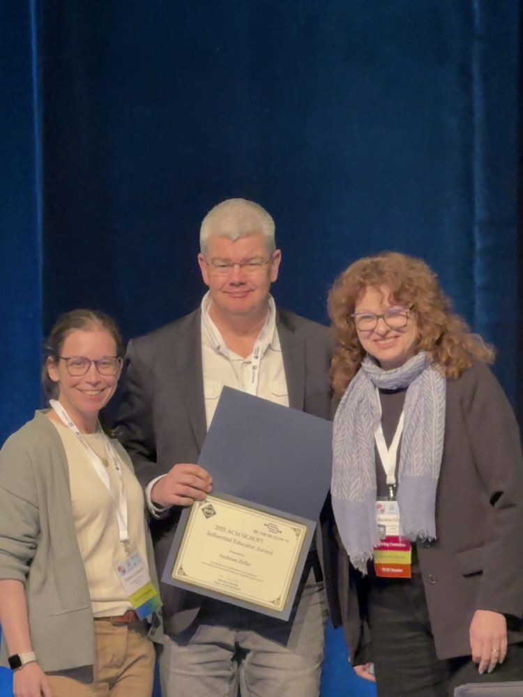 Claire Le Goues (Awards chair), Andreas Zeller (holding the award certificate), and Marsha Chechik (ACM SIGSOFT chair)