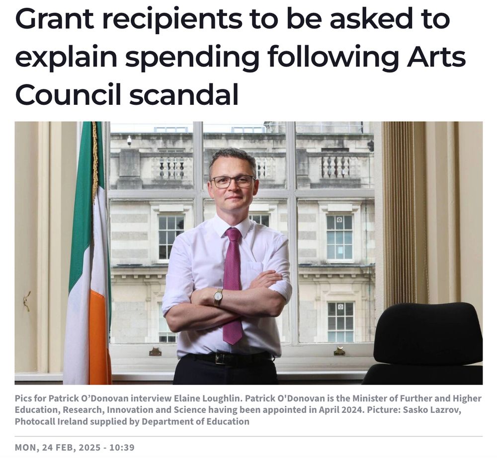 screenshot from today's Irish Examiner showing Minister Patrick O'Donovan in his office with his arms folded, standing beside the Irish flag. The headline reads Grant recipients to be asked to explain spending following Arts Council Scandal. 