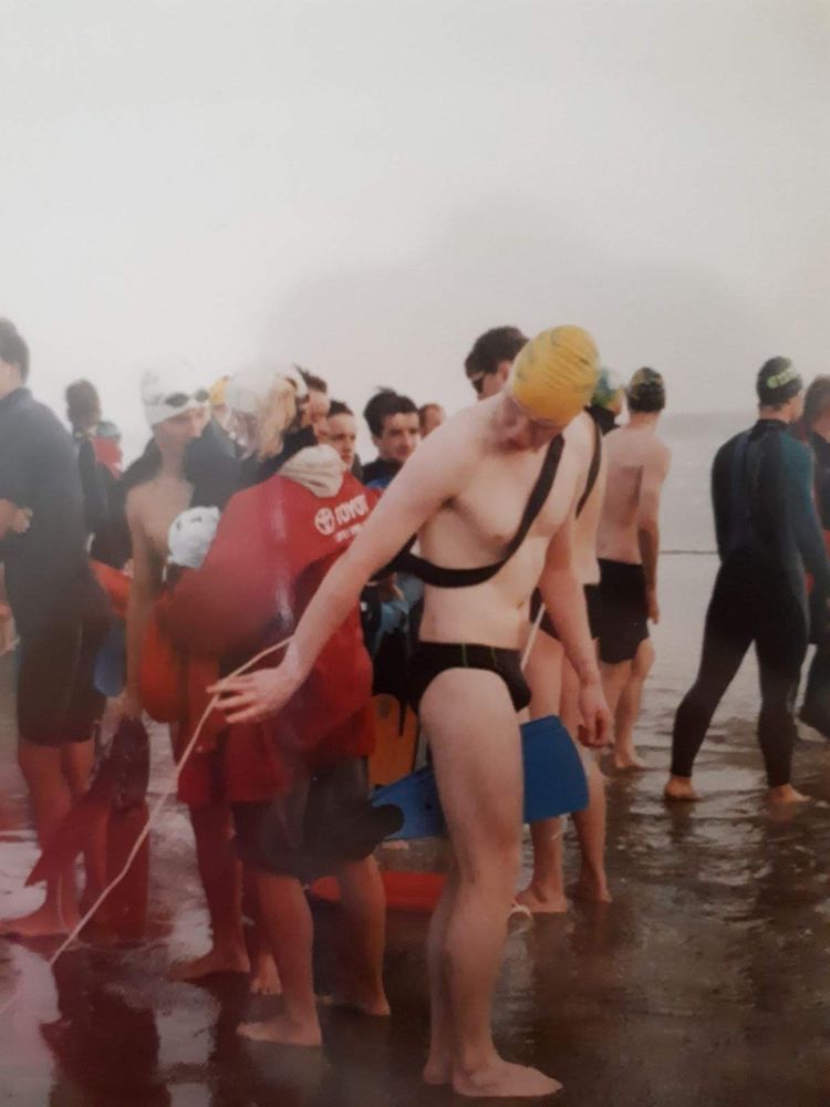 photo of a start line in a surf lifesaving competition, I am positioning the rope of my can buoy, and holding fins between my legs. 