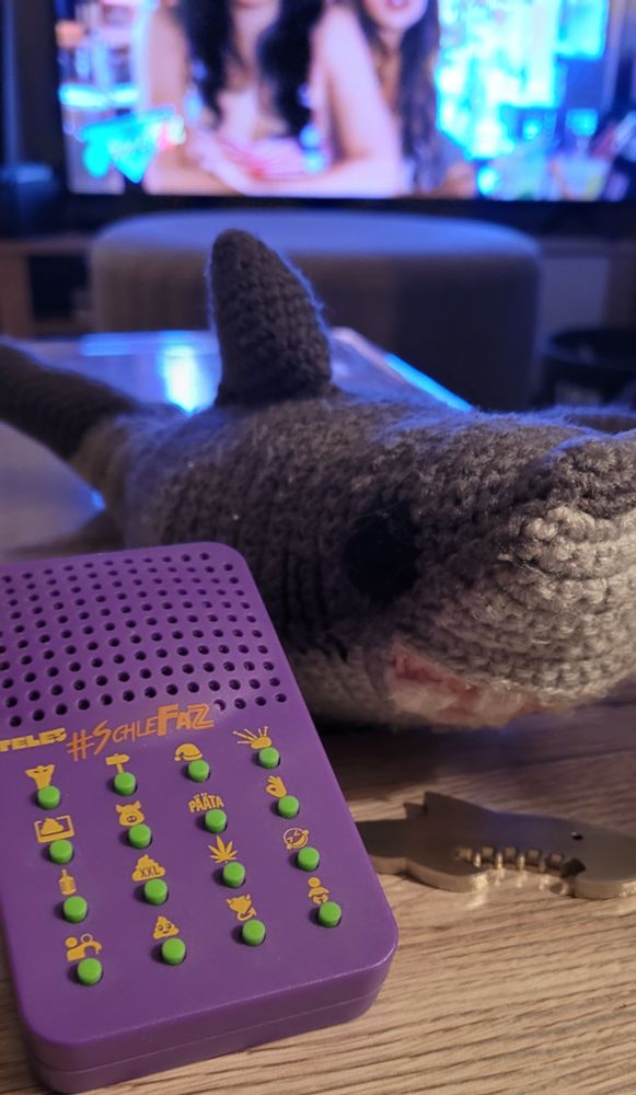 In Hintergrund läuft Schlefaz mit ZombieShark, in Vordergrund ist Haibert der Strick Hai und der Hai Flaschenöffner sowie die Schlefaz Sound Boy zu sehen.