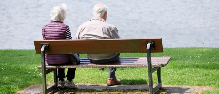An older couple sitting on a bench looking out to sea