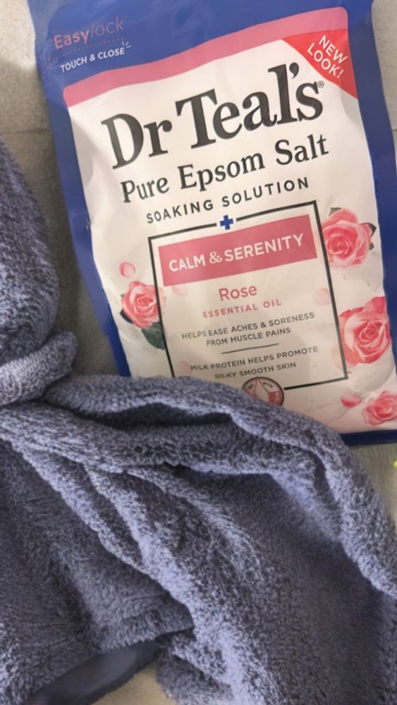 A pouch of Dr Teal’s Pure Epsom Salt soaking solution in the Rose scent is next to a towel