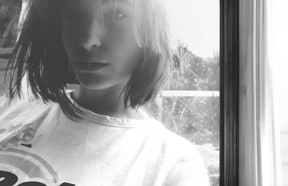 Standing near the window taking a selfie on a dirty window pane in B&W monochrome filter.