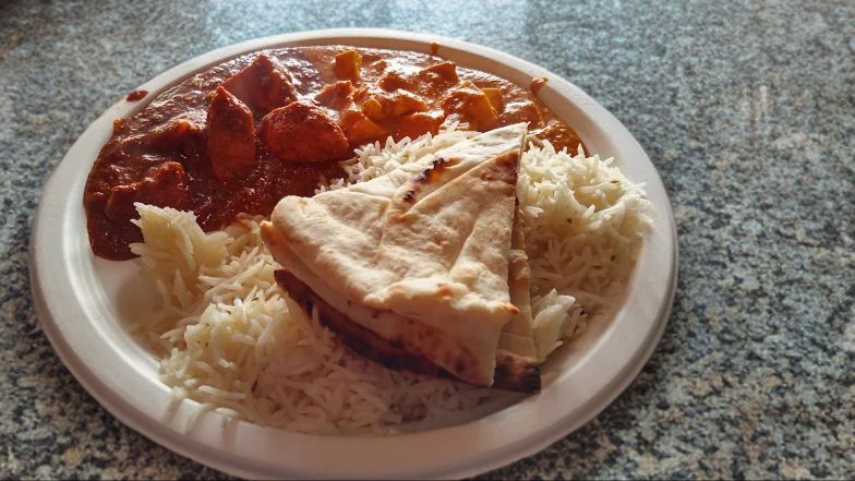 Garlic Bread w Rice and Chicken Tikka Masala served on a disposable Styrofoam plate kept on kitchen countertop 