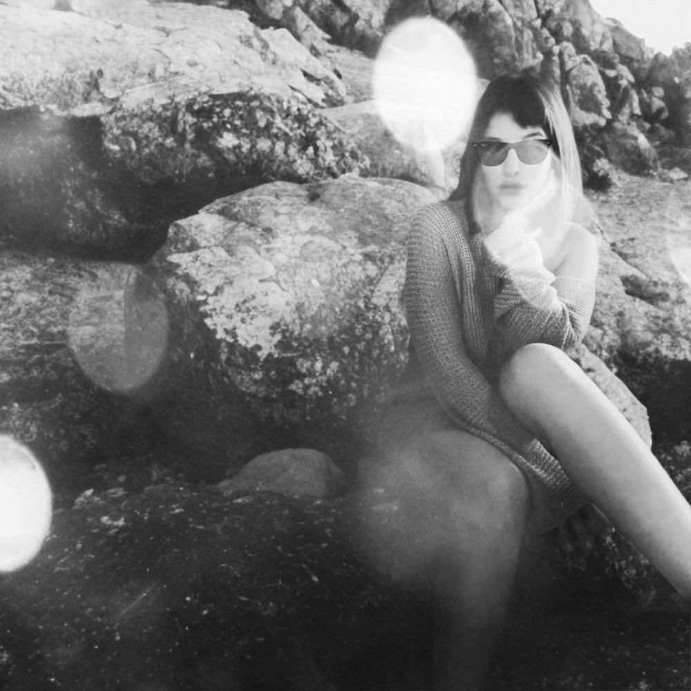 Wearing beach overalls and sunnies on rocky terrain with bokeh-lens effects in the foreground.


in a monochrome filter 