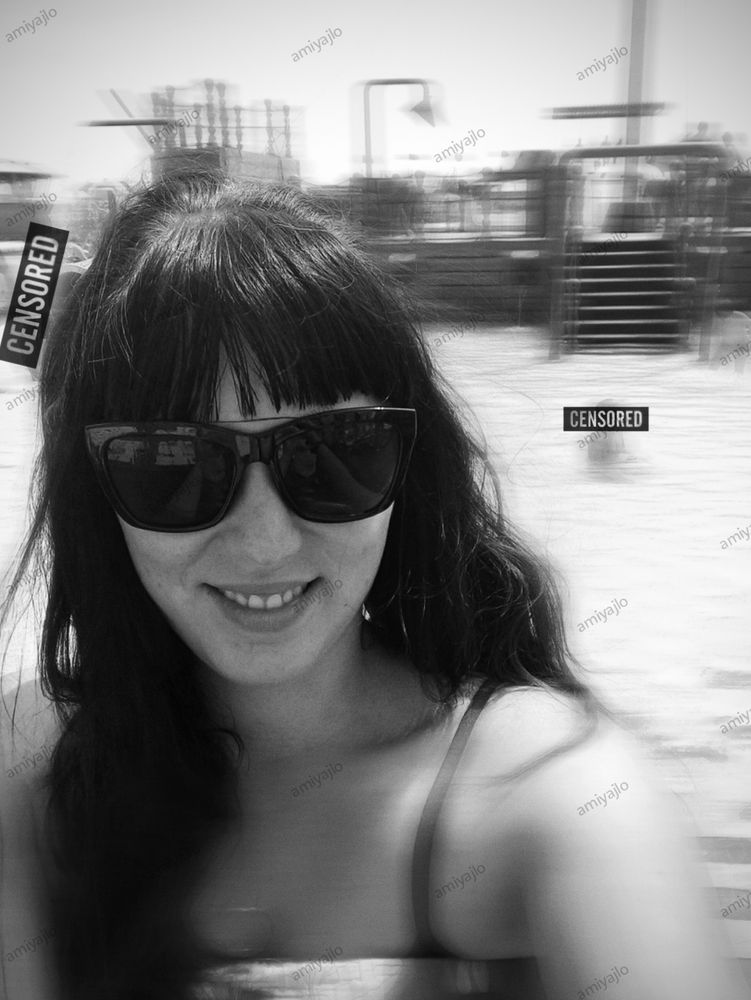 A woman with long dark hair and sunglasses smiles at the camera at the public pool
