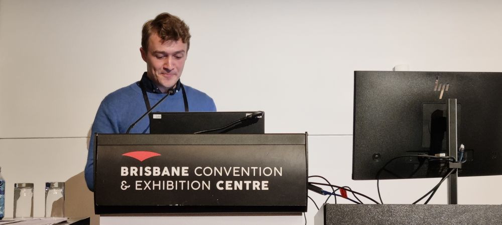 Me (in a blue jumper and at a lectern labelled &quot;Brisbane Convention & Exhibition Centre) presenting at the 30th International Population Conference.