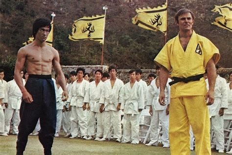 Bruce Lee and John Saxon in front of a crowd of extras in a still from Enter The Dragon