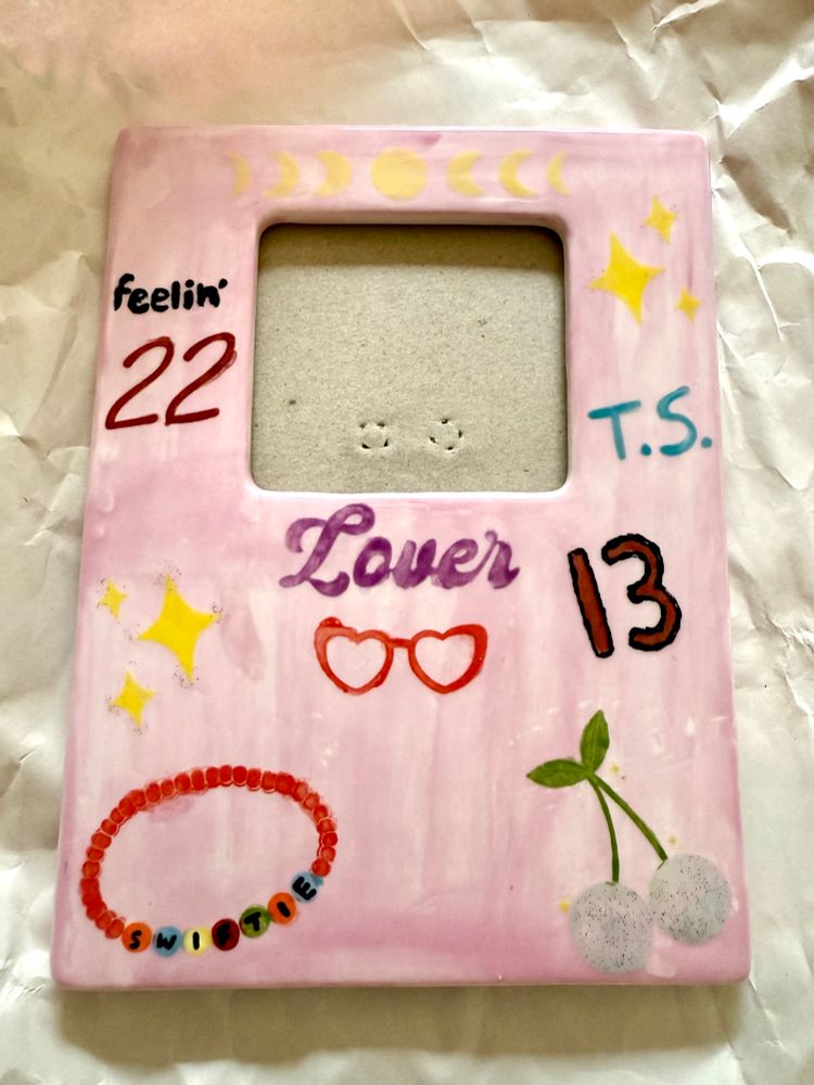 A photo frame painted with Taylor Swift themed symbols and objects after it’s been glazed in the kiln 