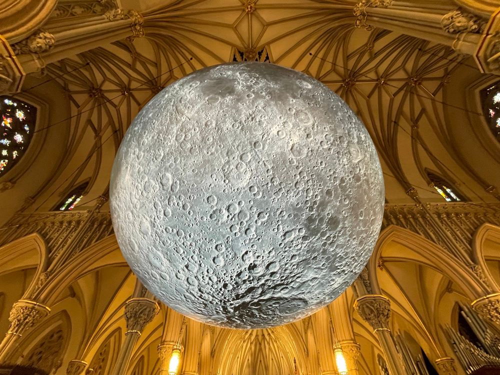 Another view of the moon sculpture from underneath, showing the ceiling ribs of the transcept behind it.