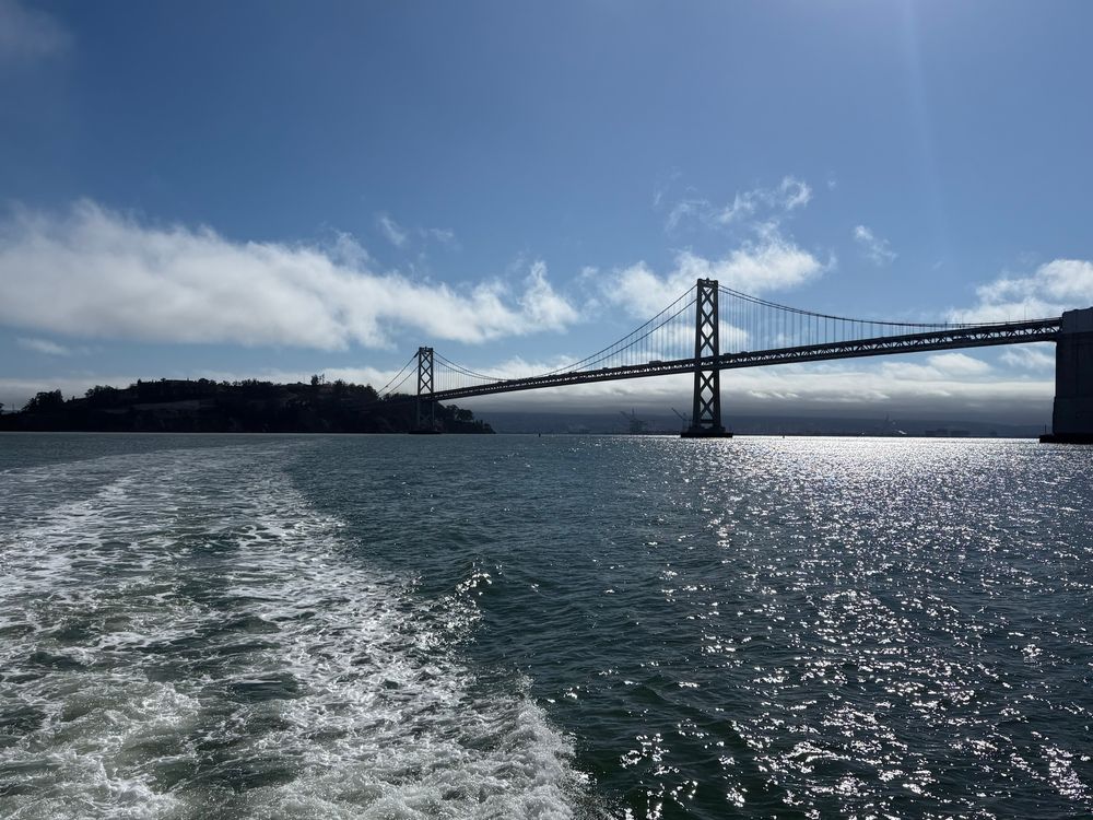 SF Bay Bridge from the back of a ferry on a sunny day.

