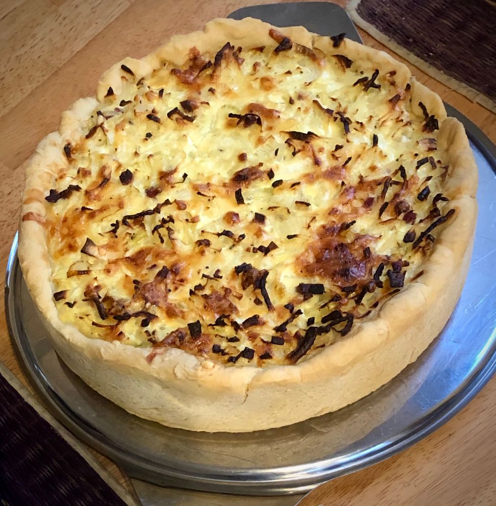Ein selbstgebackener Zwiebelkuchen auf einer silberfarbenen Platte.