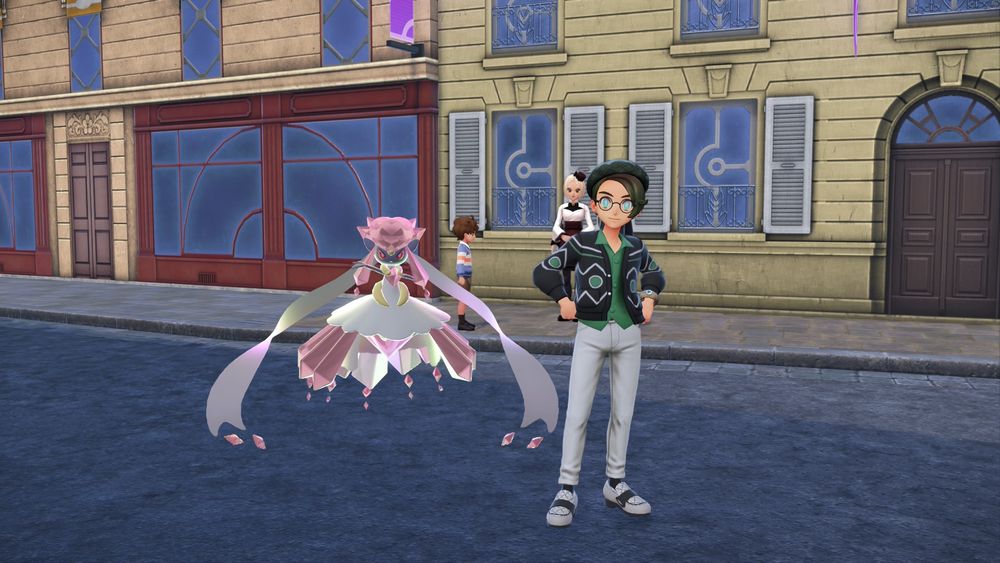 A screenshot from the game Pokémon Legends: Z-A shows a male Trainer posing on a paved street in a European-style city. Floating beside him is the Mythical Pokémon, Mega Diancie, recognizable by its large, pink, crystalline form with long, flowing ethereal ribbons.
