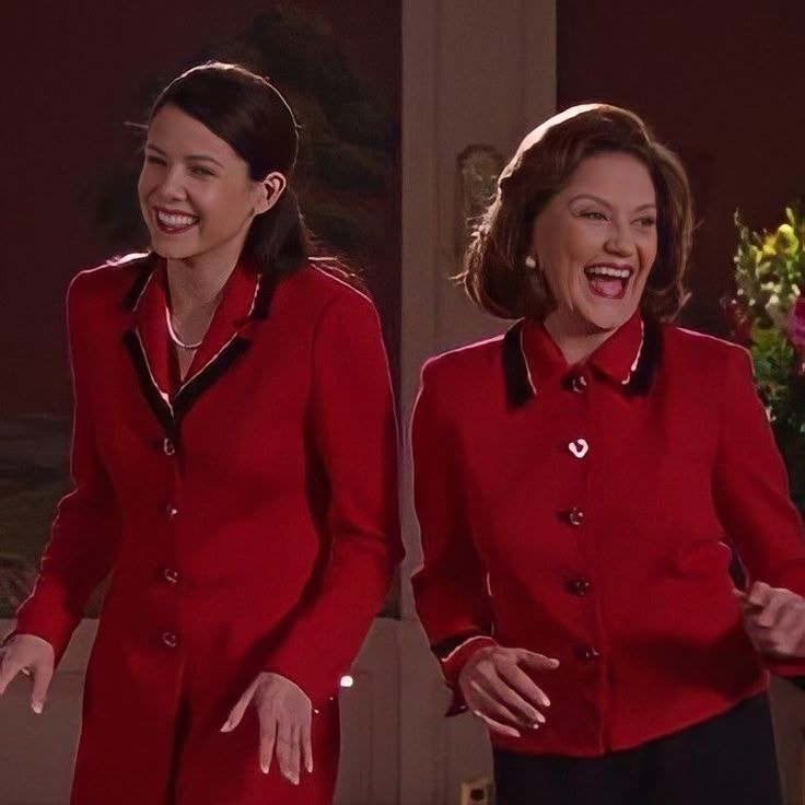 This photo features actresses Lauren Graham (left) and Kelly Bishop (right), best known for their roles as Lorelai Gilmore and Emily Gilmore on the television series Gilmore Girls.
They're laughing in matching red suits with black trim, which is an iconic look from a fashion show scene in the show.
