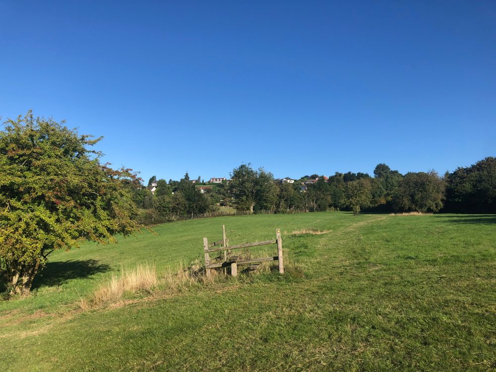 A field with a broken piece of wooden fence and a stile sat alone in the middle 
